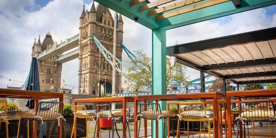A cozy patio featuring tables and chairs, set against the iconic backdrop of Tower Bridge.